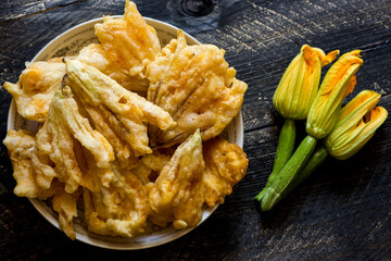 Wall Mural - Fried zucchini flowers in batter on wooden background