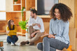 © Annika List/Westend61 - Curly hair female entrepreneur writing in book with colleagues talking in background at office