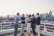 © Annika List/Westend61 - Entrepreneurs toasting wine glasses while standing on rooftop