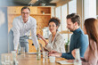 © Annika List/Westend61 - Businesswoman discussing while sitting by colleagues in office