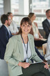 © Annika List/Westend61 - Businesswoman smiling while sitting with colleagues in conference centre