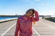 © Albert Mart√≠nez/Westend61 - Young female athlete stretching neck while standing on boardwalk during sunny day