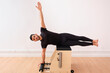 © Antonio Ovejero Diaz/Westend61 - Determined man lying sideways with arm raised on pilates chair in exercise room