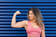© Antonio Ovejero Diaz/Westend61 - Sportswoman smiling while looking at bicep in front of corrugated wall