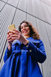 © Angel Santana Garcia/Westend61 - Smiling female professional working on smart phone in front of wall