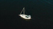 Aerial Top View Of Small Yacht With Solar Panels Sailing Sea Or River On Daybreak. Alternative Energy Source Vessel Going Sailing With Two Men On Smooth Water Surface At Dawn