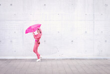 Happy Woman Holding Pink Umbrella On Footpath