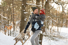 Father With Sled Holding Son While Walking In Snow During Winter