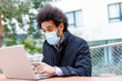 © Ignacio Ferrandiz Roig/Westend61 - Afro businessman wearing face mask working on laptop during COVID-19