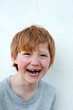 © Gianna Schade/Westend61 - Laughing redhead boy in front of white wall