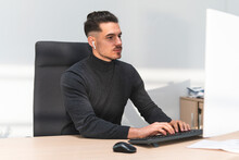 Young Businessman Working On Computer At Desk In Office