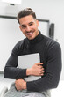 © Josu Acosta/Westend61 - Smiling young businessman holding laptop at office