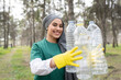 © Jose Carlos Ichiro/Westend61 - Smiling female volunteer with protective glove holding plastic bottle in forest
