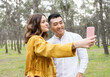 © Jose Carlos Ichiro/Westend61 - Man with beautiful woman taking selfie on smart phone at forest