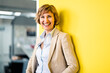 © Joseffson/Westend61 - Cheerful businesswoman leaning on yellow wall