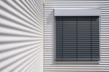 corrugated iron facade of a warehouse. Window with closed blinds. 