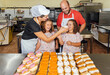 © Julio Rodriguez/Westend61 - Smiling mother feeding cake to girls while standing with man in bakery kitchen