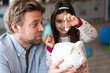 © Joseffson/Westend61 - Daughter putting coin in piggy bank held by father at home