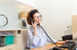 © Sus Pons/Westend61 - Receptionist talking on telephone at desk in hotel