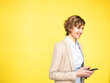 © Joseffson/Westend61 - Smiling businesswoman holding mobile phone by yellow background