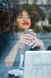 © Julio Rodriguez/Westend61 - Beautiful businesswoman day dreaming while holding iced coffee in front of laptop at cafe