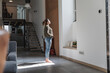 © 27exp/Westend61 - Sunlight falling on woman standing in living room at home