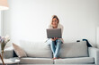 © Joseffson/Westend61 - Mid adult woman using laptop on sofa at home