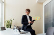 © Eugenio Marongiu/Westend61 - Thoughtful businesswoman holding digital tablet while sitting on desk in office