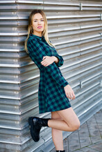 Beautiful Woman In Plaid Dress Leaning On Wall