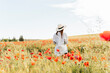 © Mar/Westend61 - Woman wearing hat standing in poppy field