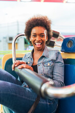 Cheerful Woman Sitting In Ride At Amusement Park