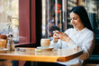 © alev/Westend61 - Smiling woman using mobile phone at cafe