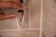 © Pete Muller/Westend61 - Woman holding faucet in bathroom