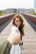 © Mikel Taboada/Westend61 - Girlfriend smiling while holding boyfriend hand on bridge