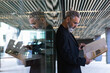 © NOVELLIMAGE/Westend61 - Hipster businessman reading business plan while standing in front of glass wall