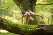 Confident woman jumping over fallen tree in forest
