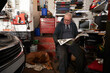 © Pete Muller/Westend61 - Senior male auto mechanic reading newspaper while sitting in garage