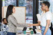 © NOVELLIMAGE/Westend61 - Smiling businesswoman doing handshake while standing in board room