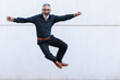 © NOVELLIMAGE/Westend61 - Carefree man with arms outstretched jumping in front of wall