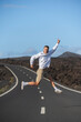 © SERGIO NIEVAS/Westend61 - Smiling male tourist gesturing and jumping over road