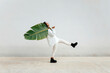 © Tania Cervian/Westend61 - Young woman dancing while carrying big banana leaf by white wall