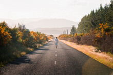 New Zealand, North Island, Rotorua, Rear View Of Young Man Walking On Road In Bay Of Plenty