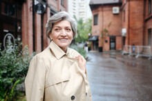 Smiling Mature Woman Wearing Trench Coat While Looking Away