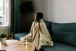 © Xavier Lorenzo/Westend61 - Sick woman looking away while wrapped in blanket at home