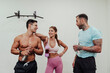 © Eva Blanco/Westend61 - Male and female athletes talking while standing in front of white wall at gym