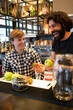 © Francesco Buttitta/Westend61 - Male bartender laughing while holding fresh fruit by trainee at bar counter