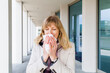 © Irina He√ü/Westend61 - Mature woman sneezing while standing at corridor