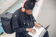 © Eugenio Marongiu/Westend61 - Young freelance worker with headphones using laptop while sitting on footpath