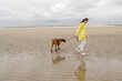 © Oxana Guryanova/Westend61 - Mid adult woman walking with dog at beach