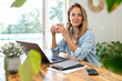 © steve brookland/Westend61 - Female entrepreneur sitting with laptop and coffee cup looking away